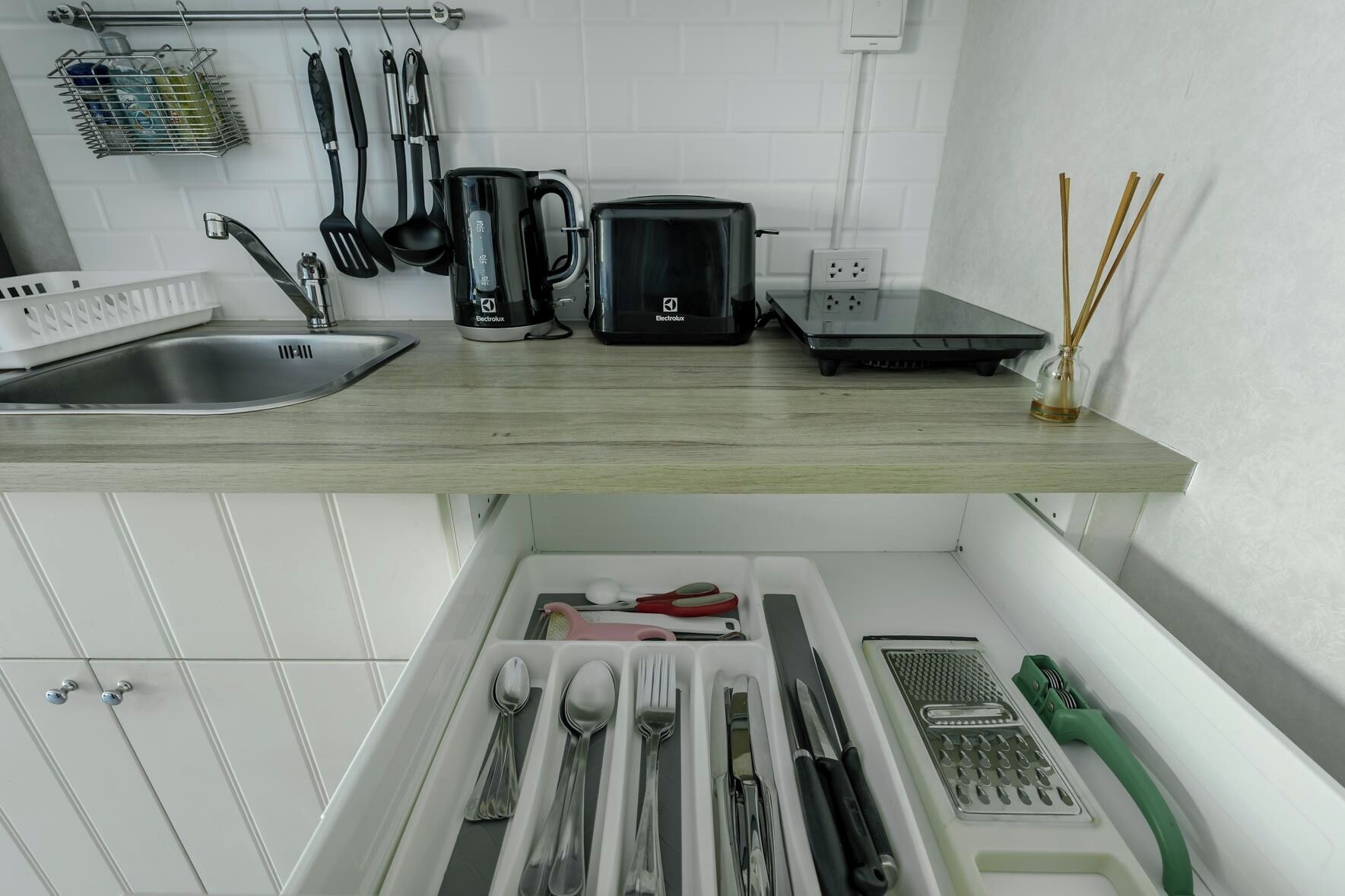 Et køkken med træbordplade, elkedel, brødrister og vask.