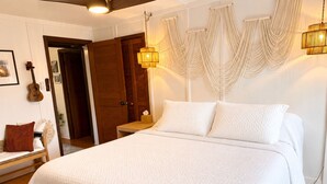 Een slaapkamer met een groot bed, een houten deur, een gitaar en een wandlamp.