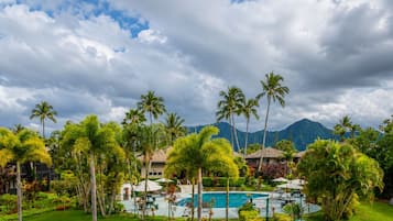 A resort with a swimming pool, palm trees, and mountains in the background.