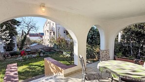 A covered outdoor area with a tiled floor, a table with a green tablecloth, and a chair. - für 4 Personen ca. 75 m² in Punat, Adriaküs by Interhome (Krk/Punat)