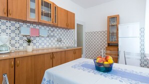 A kitchen with wooden cabinets, a white countertop, and a table with a blue tablecloth. - für 4 Personen ca. 75 m² in Punat, Adriaküs by Interhome (Krk/Punat)