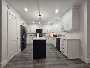 Una cocina moderna con armarios blancos, un refrigerador negro y una isla central.