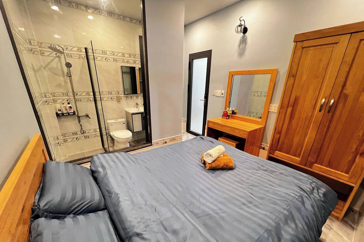 Un dormitorio con cama, armario de madera, baño con ducha y espejo.