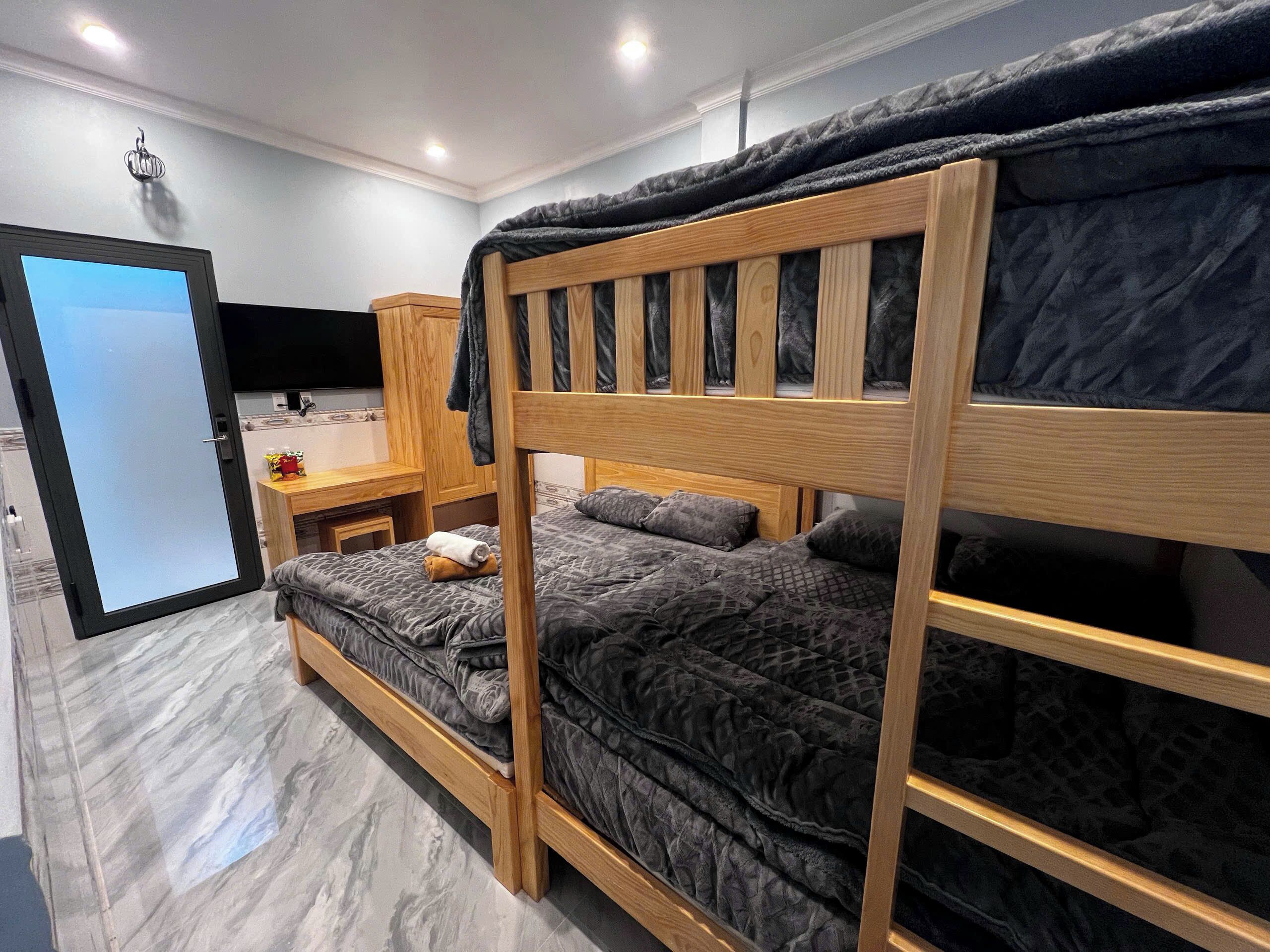 Une chambre avec un lit superposé, un bureau et une chaise, une télévision et une porte.