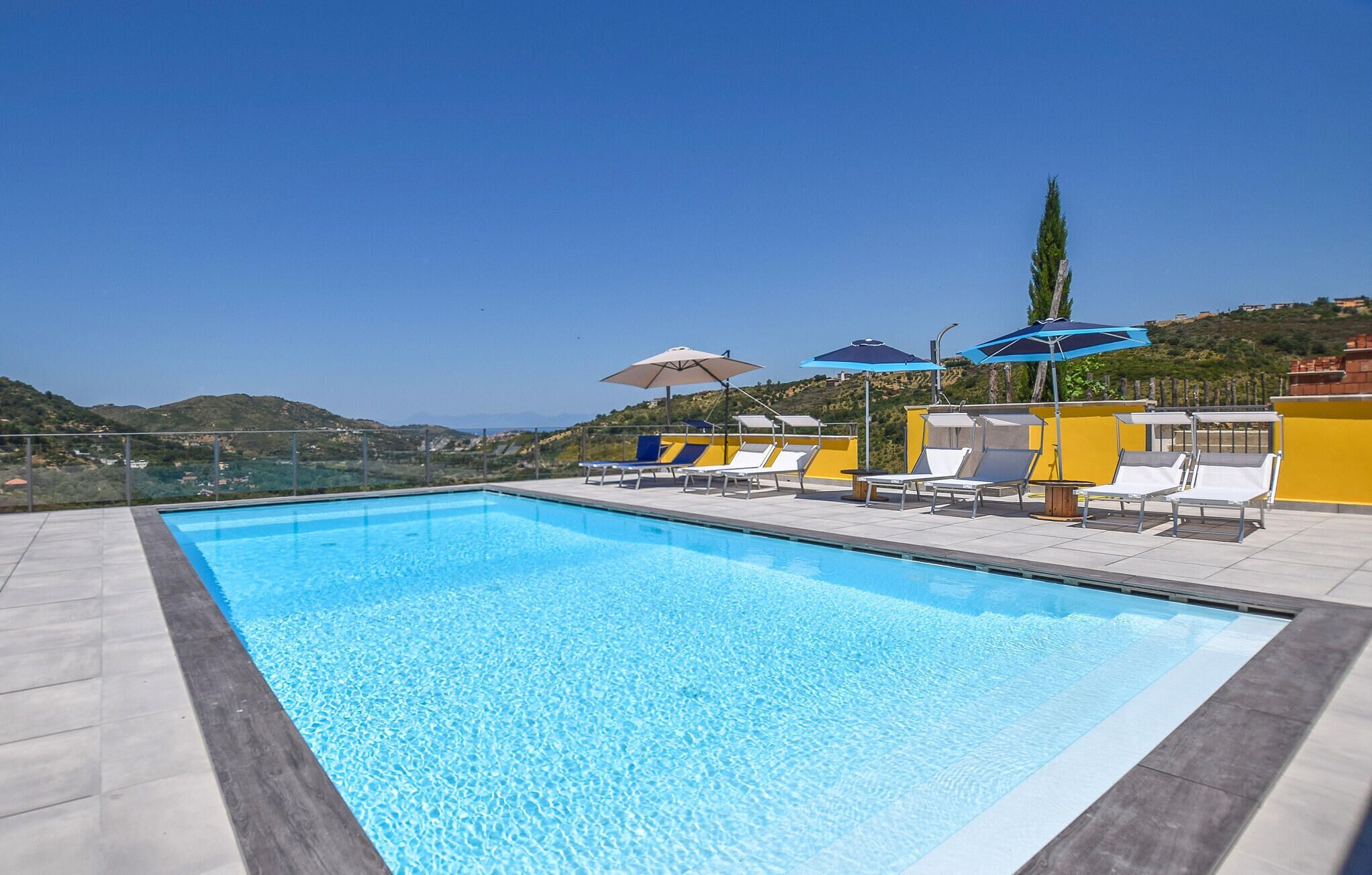 Une piscine sur le toit, agrémentée de chaises longues et de parasols, et offrant une vue dégagée sur le paysage environnant.