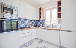 A modern kitchen with white cabinets, a built-in oven, a microwave, and a window with a view of the outdoors. - Beautiful apartment in Laureana Cilento with WiFi (Laureana Cilento)