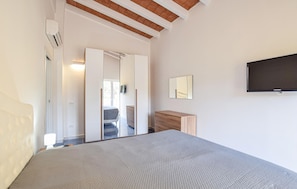 A bedroom with a bed, a wardrobe, a mirror, and a television. - Beautiful apartment in Laureana Cilento with WiFi (Laureana Cilento)