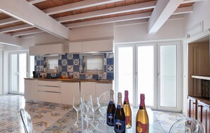 A modern kitchen with white cabinets, a tiled backsplash, and a dining area with a table set for a meal. - Stunning apartment in Laureana Cilento with WiFi (Laureana Cilento)