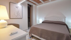Ein Schlafzimmer mit einem Bett, einem Nachttisch mit Lampe und einem gerahmten Kunstwerk an der Wand.