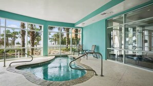 Un espace piscine au design incurvé, doté de murs en verre et offrant une vue sur l’extérieur.