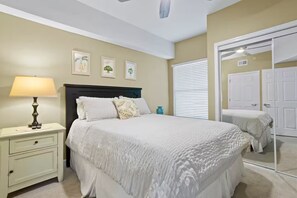Une chambre à coucher avec un lit, une table de chevet, une lampe et des tableaux encadrés accrochés au mur.