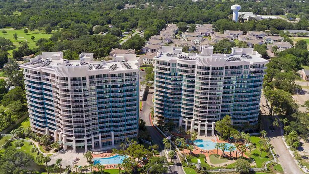 Un hôtel de grande hauteur, avec de nombreux étages, une piscine et une vue sur la verdure environnante.