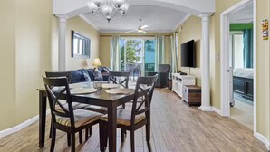 Un coin repas avec une table et des chaises, un canapé, un téléviseur et un balcon avec vue.