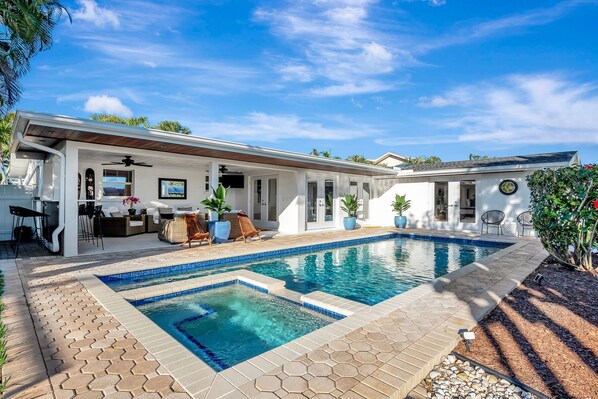A modern house with a swimming pool, outdoor seating, and a patio area.