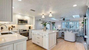 Une cuisine moderne avec des meubles blancs, des appareils en acier inoxydable et un îlot central.