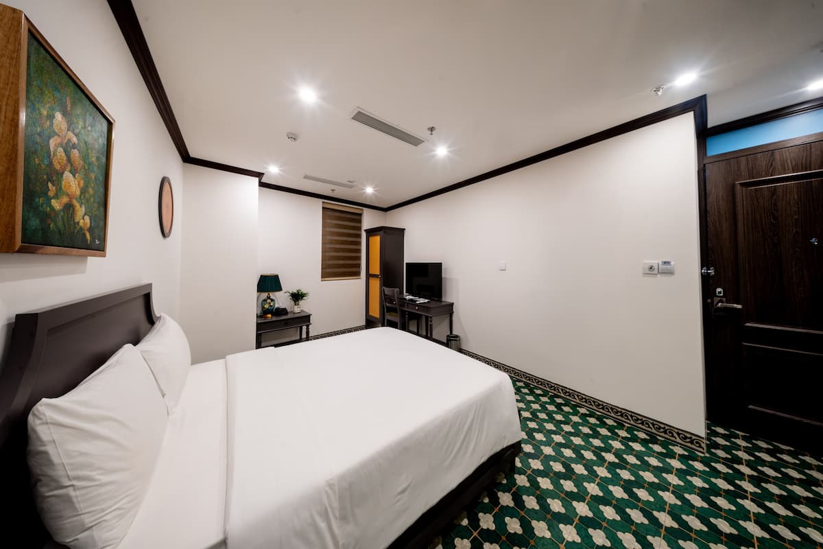 Una habitación de hotel con una cama grande, un escritorio con una silla, un televisor y una puerta.