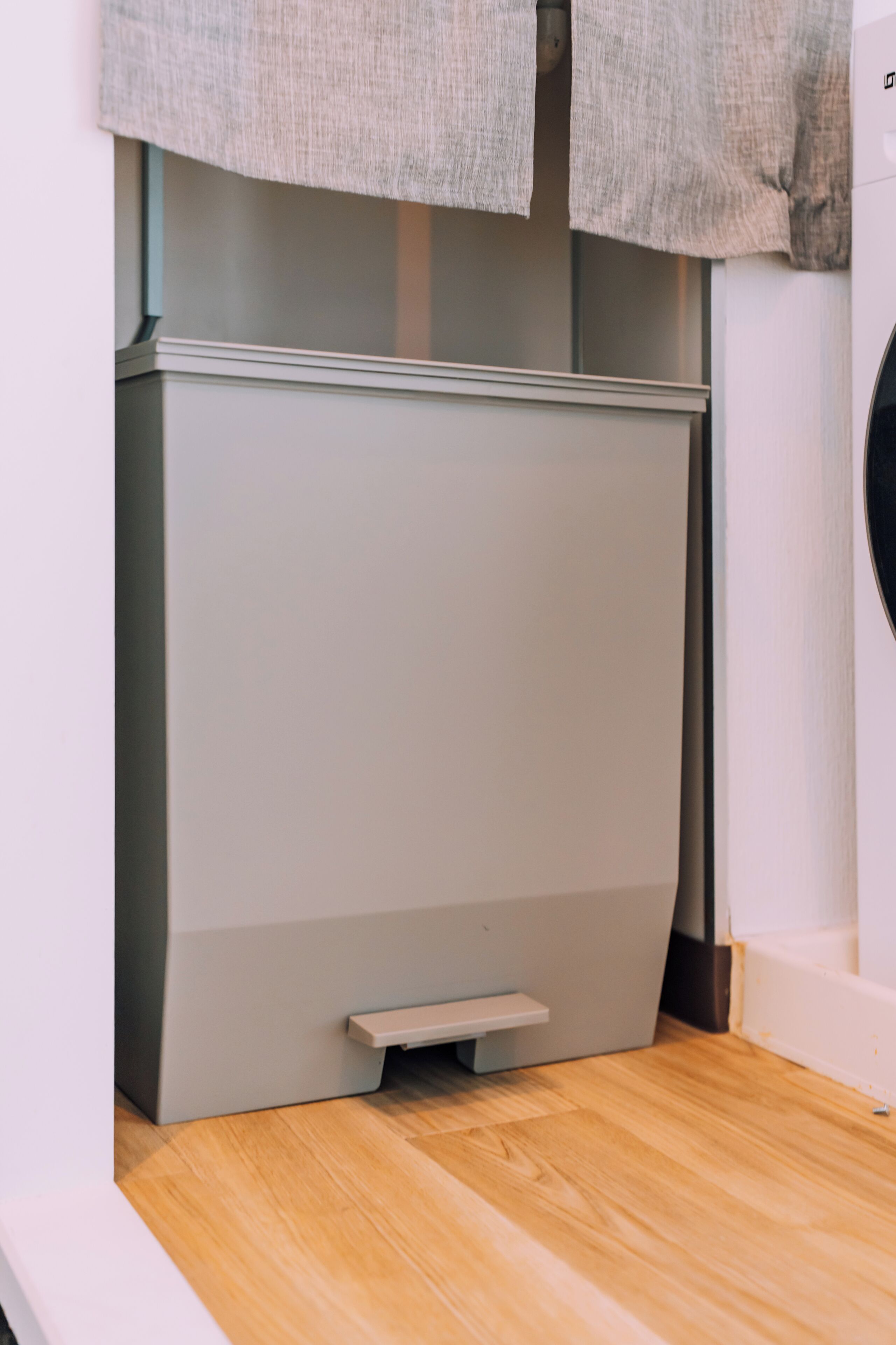A compact, modern room with a built-in washer and dryer, a small wooden bench, and a light-colored floor.