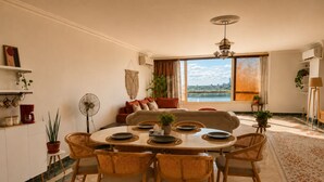 Un comedor con una mesa redonda, sillas de mimbre y vistas amplias a través de grandes ventanales.