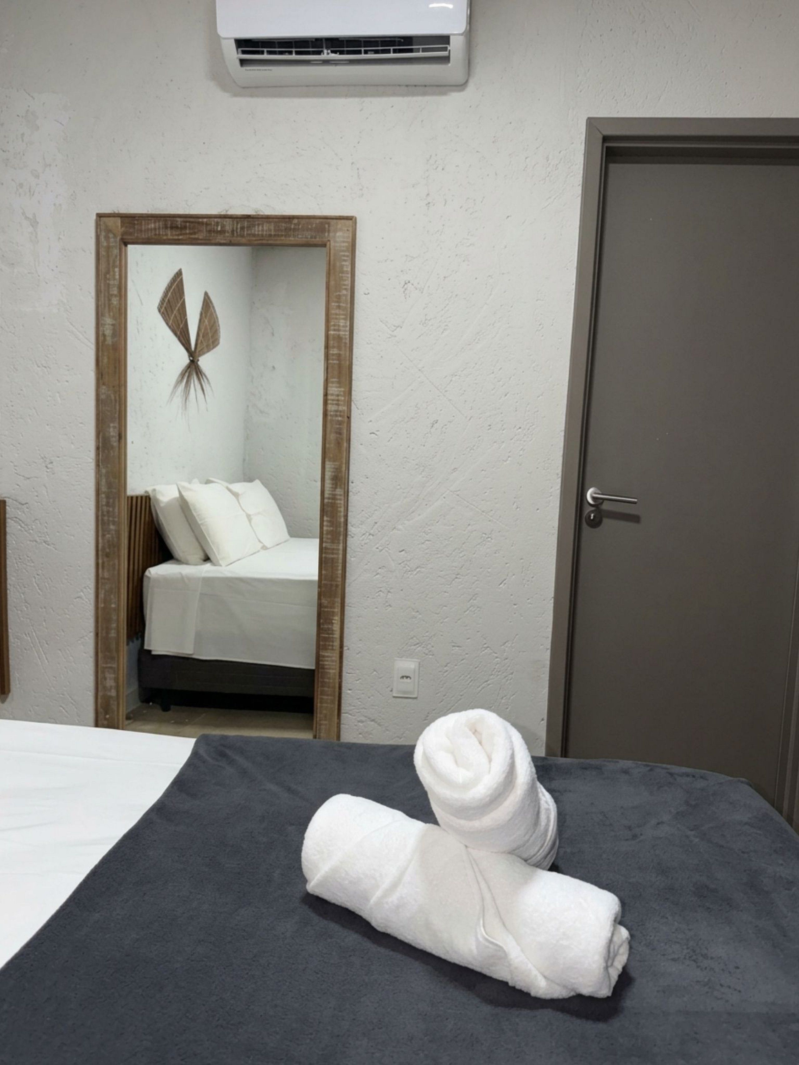 Ein Hotelzimmer mit Bett, Tür, Klimaanlage und Spiegel mit Dekoration.