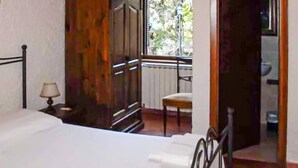 A bedroom with a bed, a chair, a nightstand, and a window with a view of greenery outside. - 6 bedroom nice home in Orbetello (Orbetello)