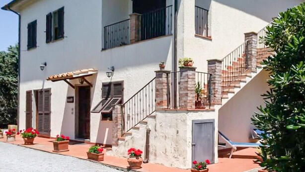 A two-story building with a staircase, potted plants, and a small outdoor seating area. - 6 bedroom nice home in Orbetello (Orbetello)