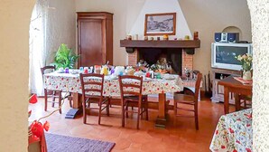 A dining area with a fireplace, wooden chairs, and a table set for a meal. - 6 bedroom nice home in Orbetello (Orbetello)