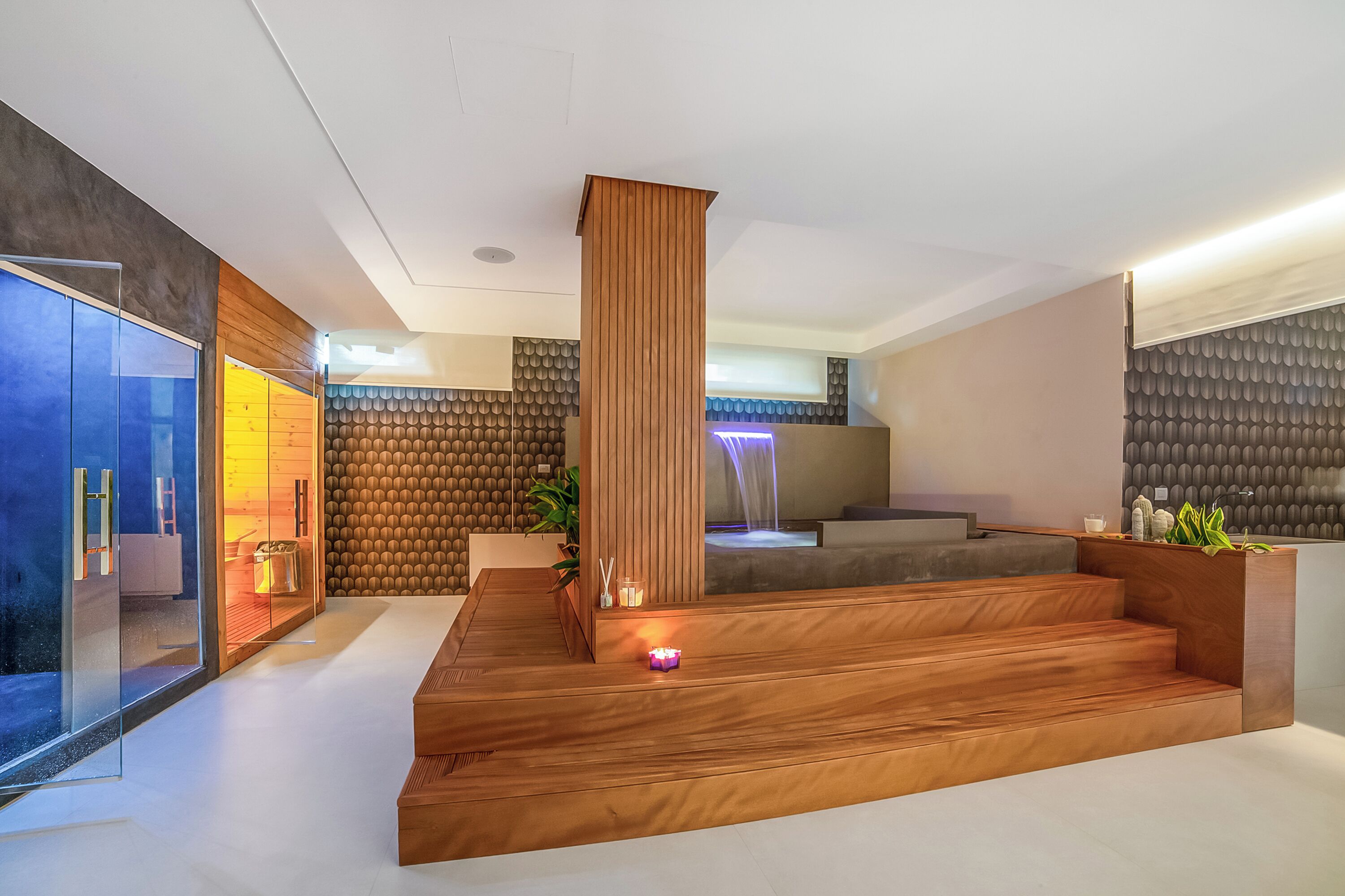Un intérieur moderne avec un comptoir d’accueil en bois, un escalier et un espace salon.