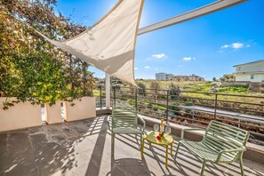 Un balcón con una mesa y sillas, una botella de champán y vistas a un paisaje verde y edificios.