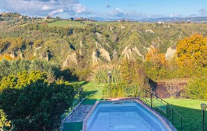 Une piscine offrant une vue sur un paysage vallonné et une ville située au loin.