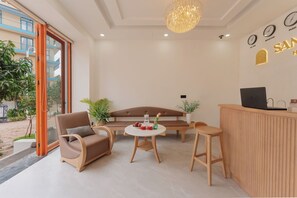 A modern hotel lobby with a reception desk, seating area, and large windows. - Santori Hòn Thơm Hotel (Phu Quoc)