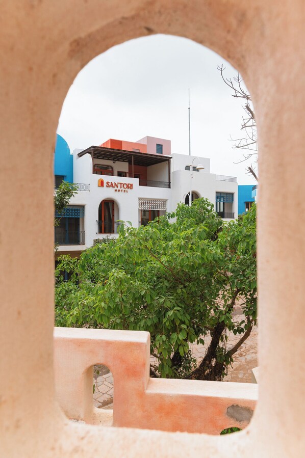 A view through an archway of a building with a sign that reads "Santori Hotel". - Santori Hòn Thơm Hotel (Phu Quoc)