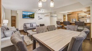 Een moderne woonkamer met een eethoek, een keuken en een groot raam met uitzicht op de bergen.