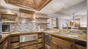 Een moderne keuken met houten kastjes, een betegelde achterwand en roestvrijstalen apparatuur.