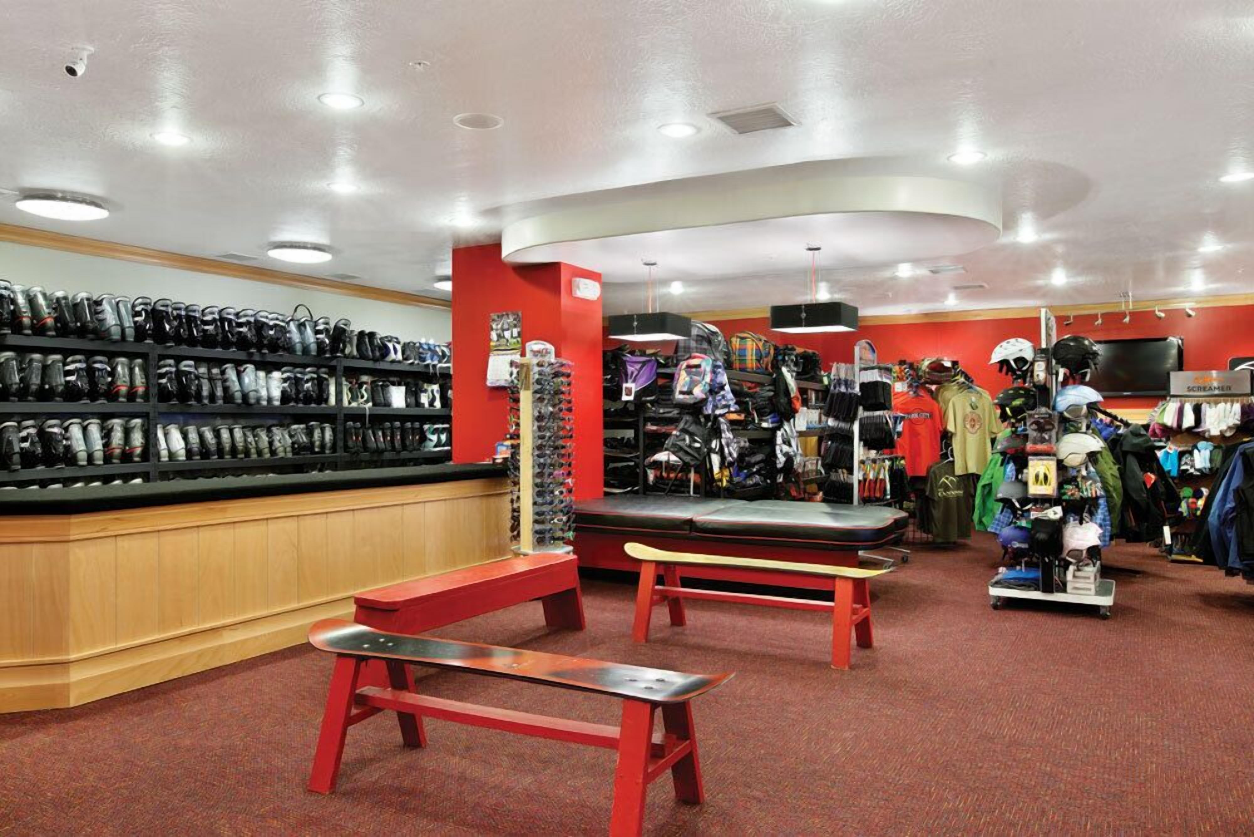 A shoe store with shelves of shoes, a bench, and a display of helmets.