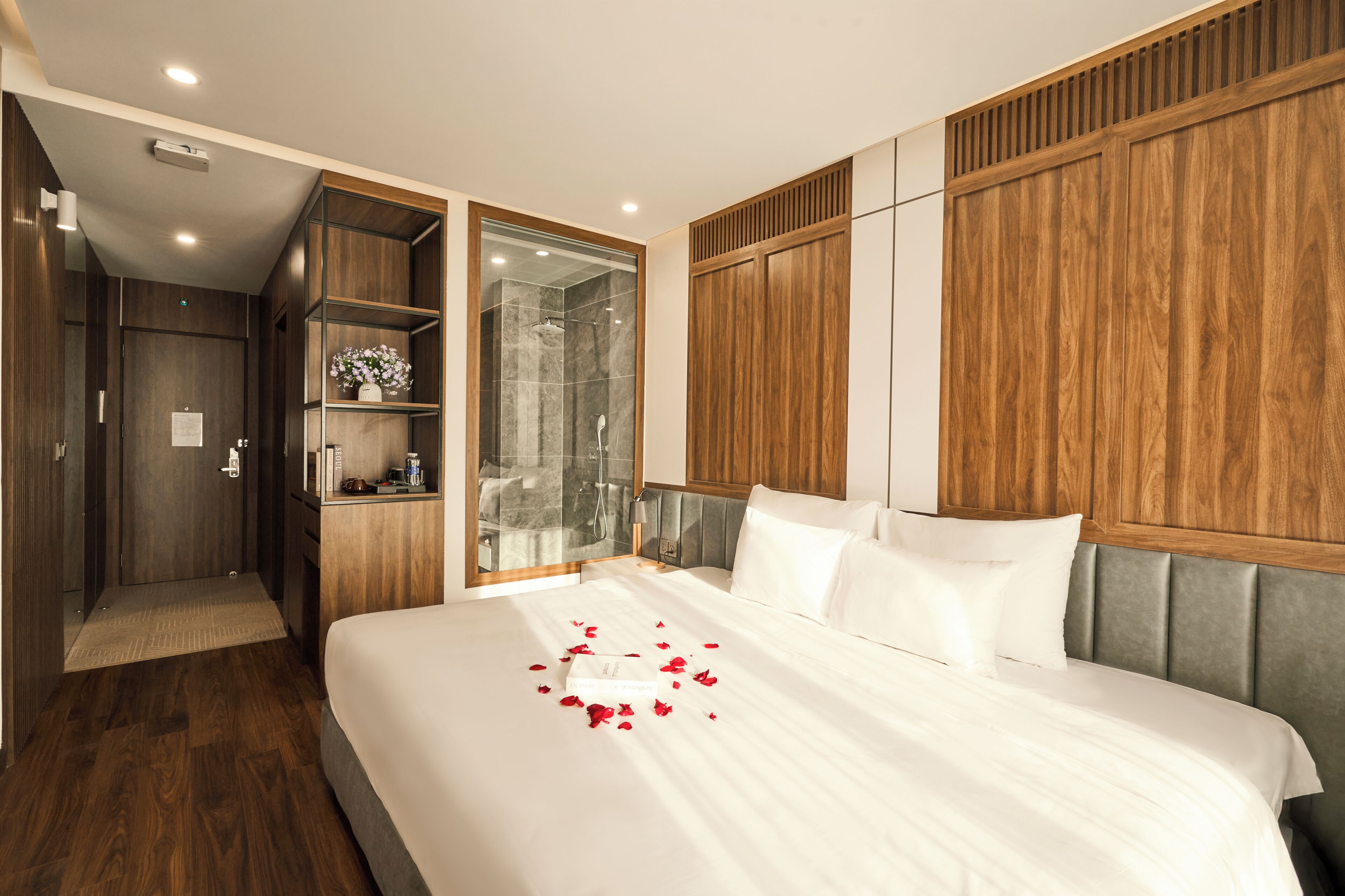 A hotel room with a large bed, a walk-in closet, and a shower area.