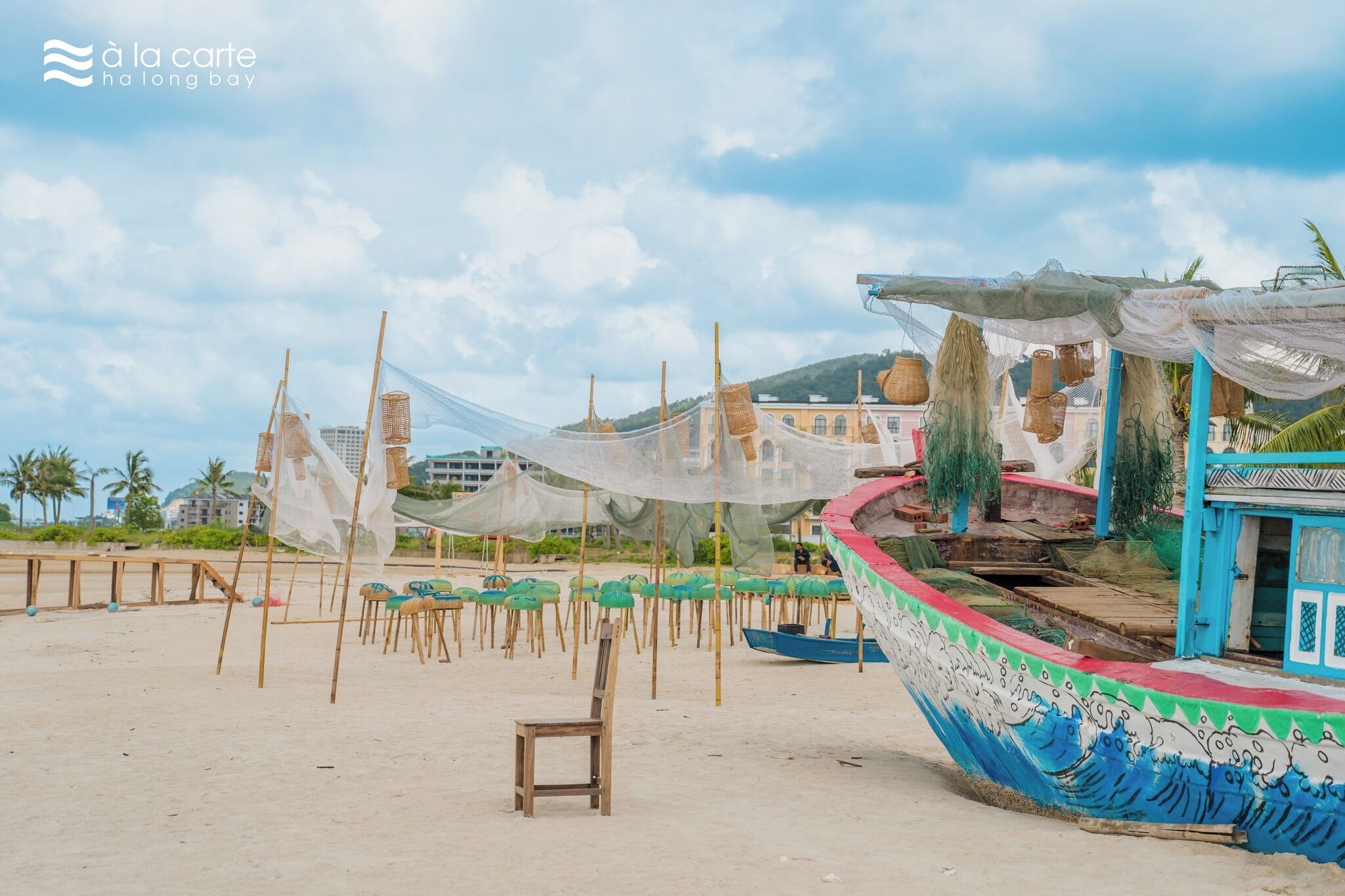 Escena de playa con un barco grande, sillas de playa y un edificio pequeño.