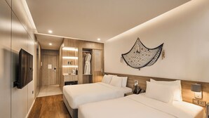 Ein Hotelzimmer mit zwei Betten, einem Schrank, einem Fernseher, einem Nachttisch und einer Wandlampe.