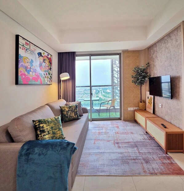 Una sala de estar moderna con un sofá, un televisor y un balcón con vistas.