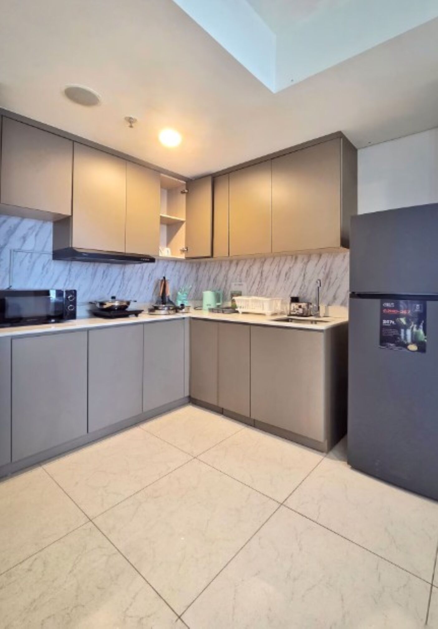 Una cocina moderna con gabinetes grises, una estufa negra y un salpicadero de mármol.