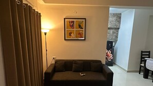 Een woonkamer met een bank, een kamerbreed tapijt, een kunstwerk aan de muur en een eethoek met een tafel en stoelen.