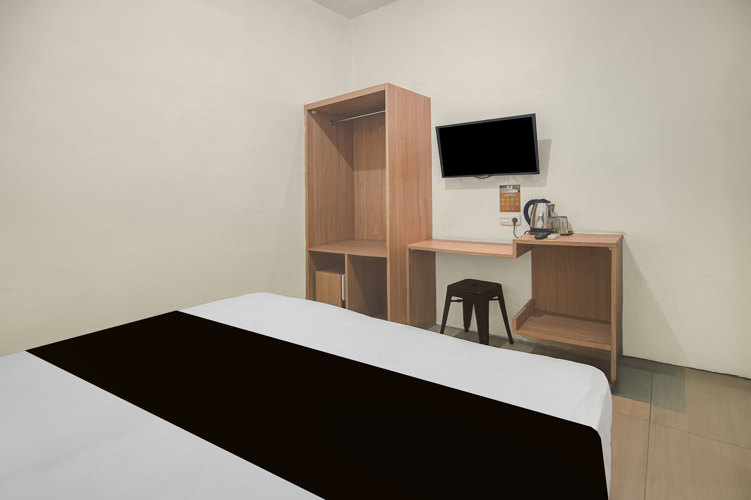 Una habitación con cama, escritorio, silla, televisor y estante.