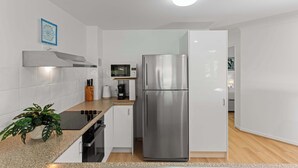 A modern kitchen with white cabinets, stainless steel appliances, a microwave, and a coffee maker. - Noosa Hill Getaway - Walk to Beach + Shared Pool (Noosa Region)