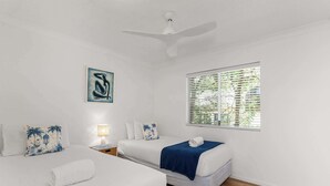 A hotel room with two beds, a ceiling fan, a window with blinds, a wall-mounted artwork, and a bedside lamp. - Noosa Hill Getaway - Walk to Beach + Shared Pool (Noosa Region)