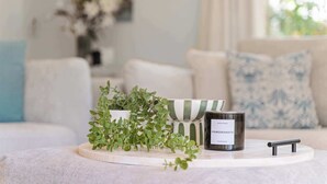 A candle on a tray with a label, a potted plant, and a candle holder. - Noosa Hill Getaway - Walk to Beach + Shared Pool (Noosa Region)