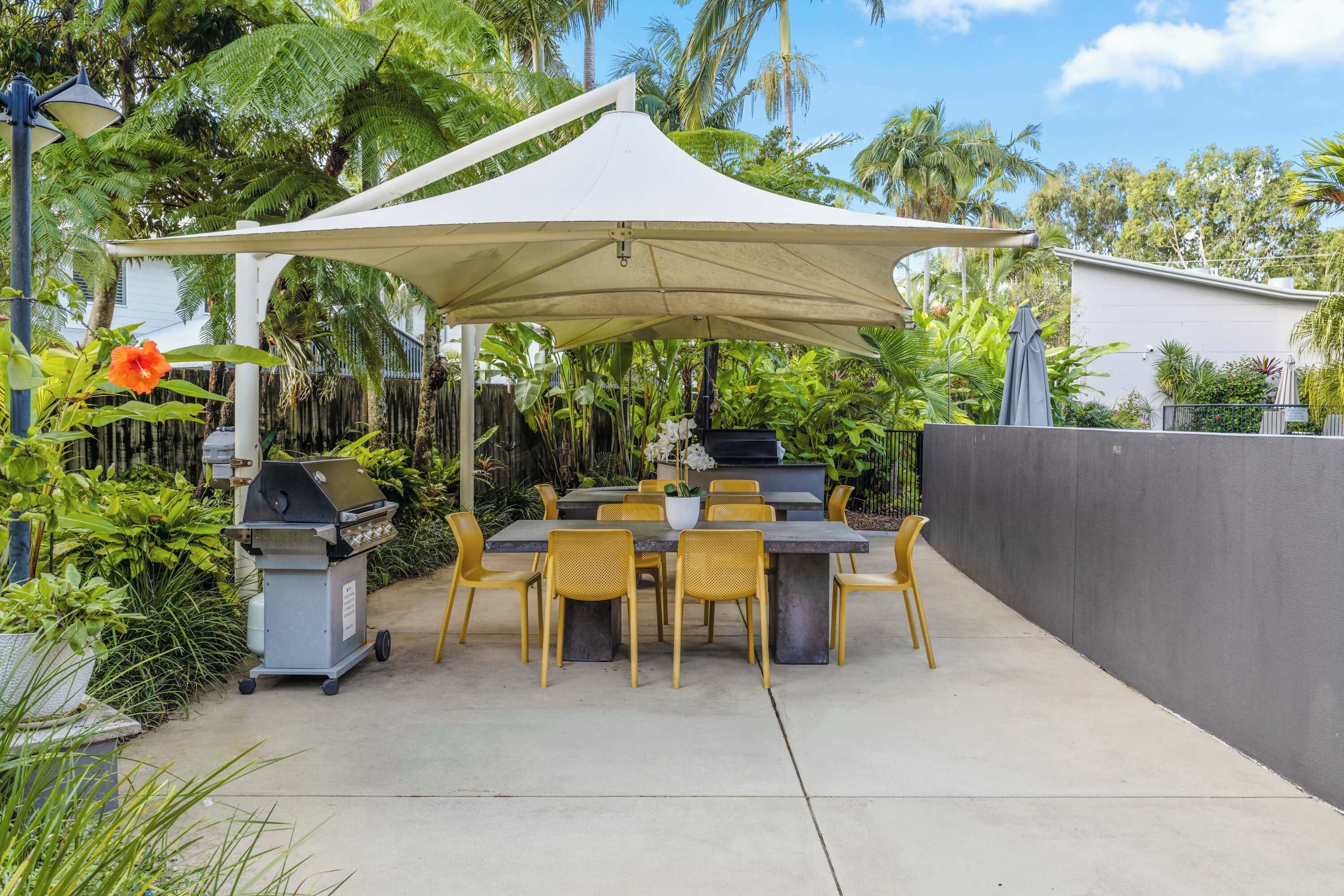 Une terrasse extérieure avec une table et des chaises, un barbecue et un auvent.