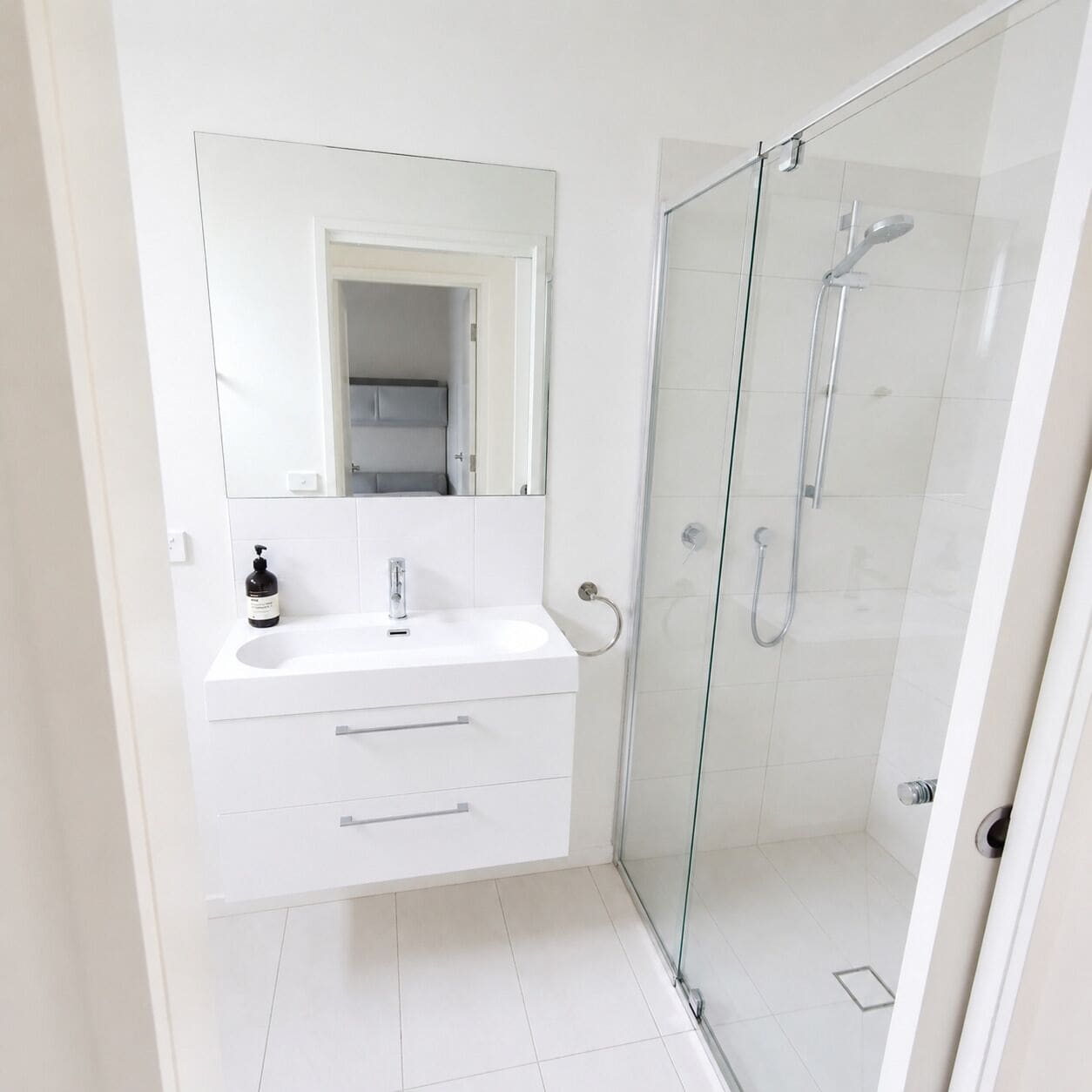 A modern bathroom with a glass-enclosed shower, a white sink, and a mirror above the vanity.