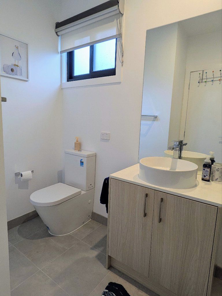 A bathroom with a toilet, sink, and mirror.