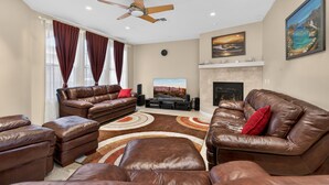 A living room with leather sofas, a fireplace, and a ceiling fan. - 30plus Day Stays,5BR Retreat,Near North Mountain (Phoenix)