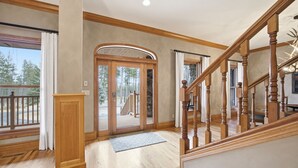 Ein geräumiger Flur mit Holzboden, einer Holztreppe und einer Glastür, die zu einem Außenbereich führt.