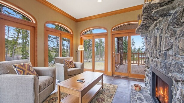 Ein geräumiges Wohnzimmer mit Kamin aus Stein, großen Bogenfenstern und einer gemütlichen Sitzecke.